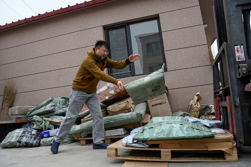 A man transfers packages containing wedding photos, sent from clients to be shredded, onto a forklift in Langfang, in northern China\'s Hebei province, March 27, 2024.