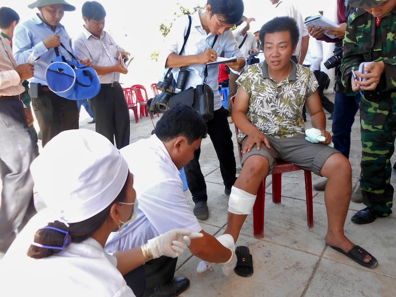 A fisherman (C) receives medical treatment upon his arrival home, after his boat was rammed and then sunk by Chinese vessels near disputed Paracels Islands, at Ly Son island of Vietnam\'s central Quang Ngai province May 29, 2014.