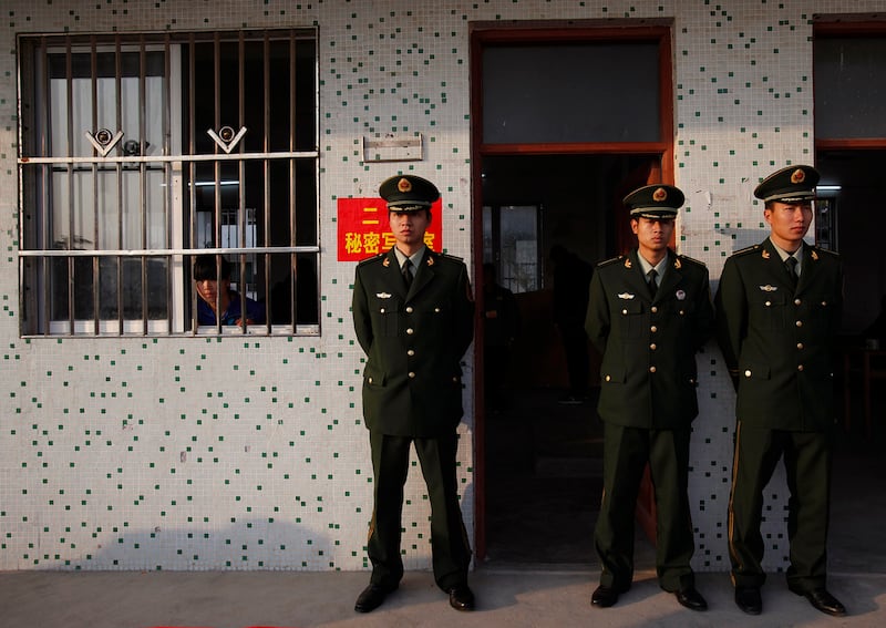 An election worker, left, looks out from a classroom guarded by police officers during vote counting at a school turned into a polling station in Wukan village in Lufeng, Guangdong province, Feb. 1, 2012.