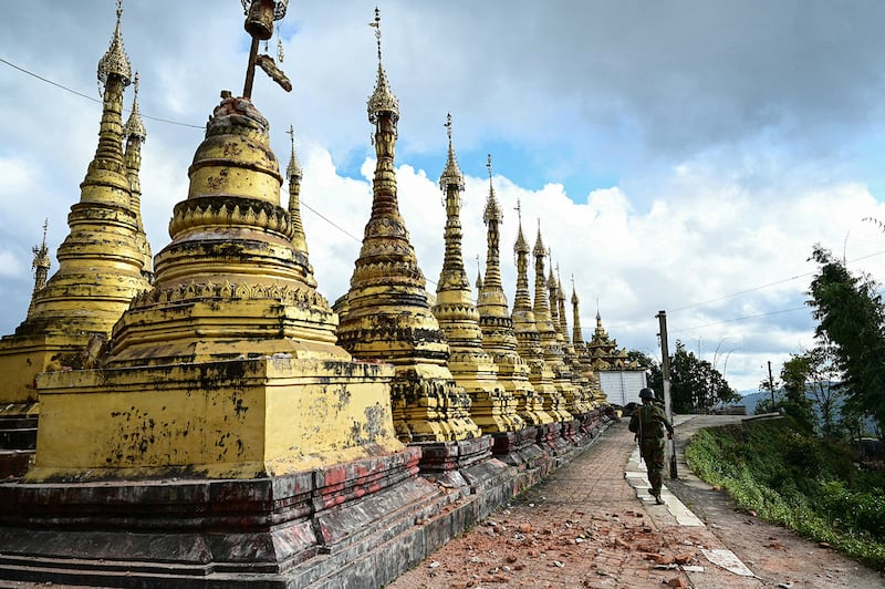 A member of the Ta\'ang National Liberation Army walks past damaged pagodas amid clashes with Myanmar’s military in Namhsan township in Myanmar\'s northern Shan State, Dec. 12, 2023.