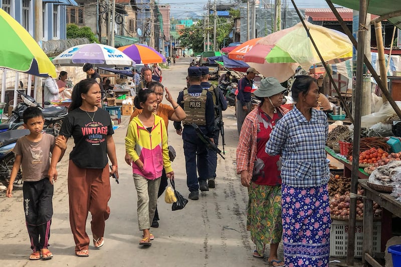 Armed police walking past people at a market area in Lashio in Myanmar\'s northern Shan state on Sept. 10, 2024, after the Myanmar National Democratic Alliance Army (MNDAA) seized the town from Myanmar\'s military in August. (AFP Photo)